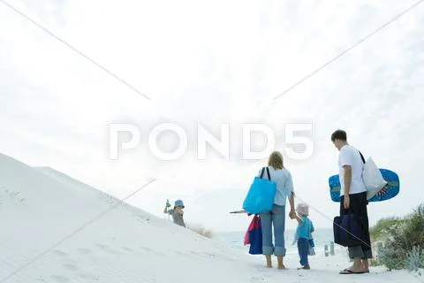 Family Walking Through Dunes To Beach