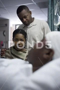 Family Watching Boy In Hospital Bed With Head Bandages