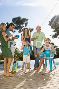 Family On A Wooden Terrace By A Pool