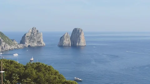 Famous sea stack Faraglioni and coastal mountains. Watercrafts float near Capri Stock Footage 100743555