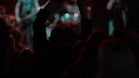 Fan clapping hands above head at concert under blue light truss Stock Footage 334351407