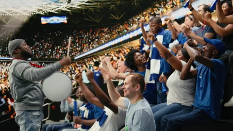 Fan leader with megaphone and drum energizing soccer supporters in stands Video stock 335674445