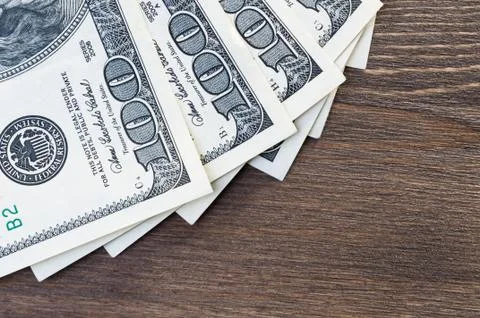 A fan of one hundred dollar bills on a dark wood background. View from above. Stock Photos