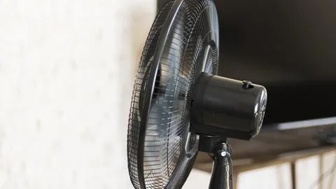 A fan is working in a space during a warm summer afternoon. The blades of the Stock Photos
