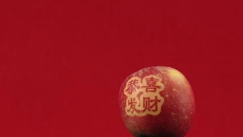 Fancy Chinese New Year Fortune Fuji apple spins against red background Stock Footage 331289970
