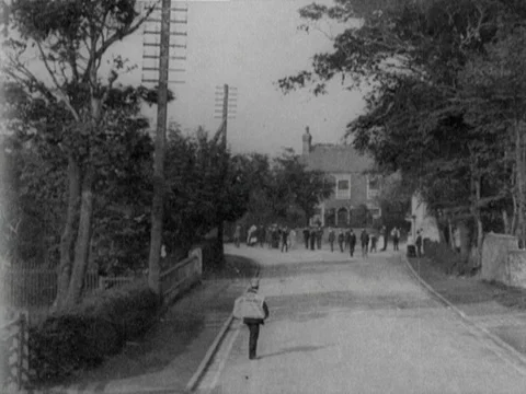 Fancy dressed people walking road, talking to each other, houses in back, 1902 Stock Footage 136682014