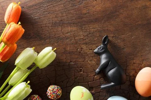 Fancy Easter eggs and tulips with decoration rabbit on wooden background abov Stock Photos