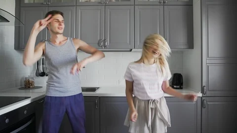 Fancy funny young people smiling, fooling and dancing together in the kitchen at Stock Footage 127484087