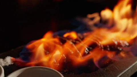 A fancy Japanese beef steak is crowned with flames. The theatrical display adds Stock Footage 249333369