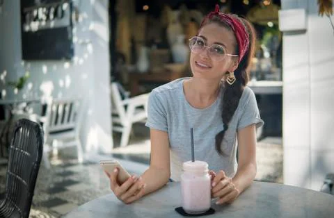 Fancy model in red headscarf and round glasses posing with a phone outdoors 스톡 사진