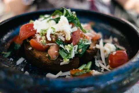 In a fancy restaurant, bread with tomato herbs and parmesan are arranged on a be Stock Photos