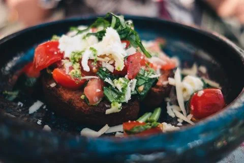 In a fancy restaurant, bread with tomato herbs and parmesan are arranged on a be Stock Photos