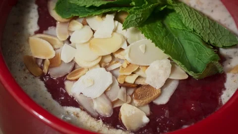 A fancy vegan meal of nuts, dried fruit, greens and jelly in a red deep plate. Stock Footage 257762583