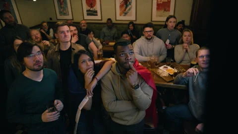 Fans crowd together watch match broadcast in sports pub on TV Stock Footage 267686591