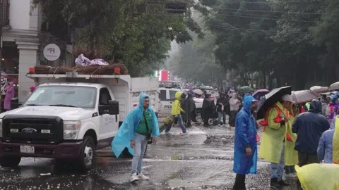 Fans in rain ponchos walk down a wet street Stock Footage 345278440