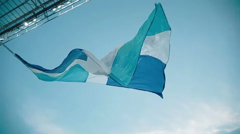 Fans in the stadium develop a blue flag on a background of blue sky Stock Footage 49827212
