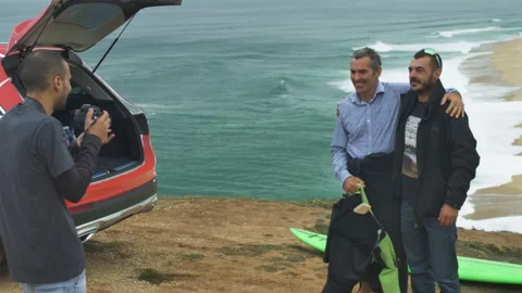Fans taking selfie with pro surfer Garrett McNamara with ocean behind them Stock Footage 155998797