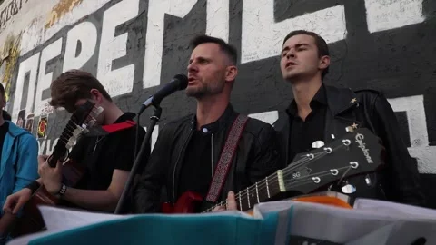 Fans of Viktor Tsoi sing a song with a guitar on the background of the Tsoi Wall Vídeo Stock 150230382