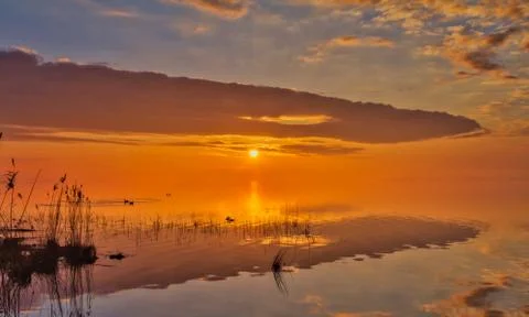 Fantastic cloud formations with reflections in the water, at sunrise on the l Stock Photos