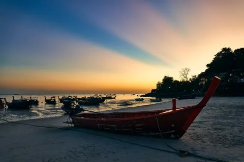 Fantastic sunset with sun light rays on tropical island and boats on beach Stock Photos