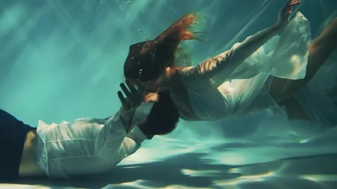 Fantasy couple man king and woman fashion model posing underwater dark blue sea Stock Footage 243563396
