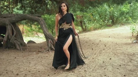 Fantasy goth woman holding pulling iron chains stretches across ground. Sexy Stock Footage 311949471