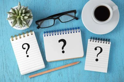 Faq concept with question marks on notepads on blue wooden table, top view 库存照片