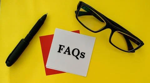 FAQs text on white post it note with pen, glasses and yellow background Stock Photos
