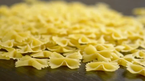 Farfalle closeup fall on a wooden table, raw pasta Stock Footage 112072625