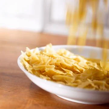 Farfalle falling onto a deep plate Stock Photos
