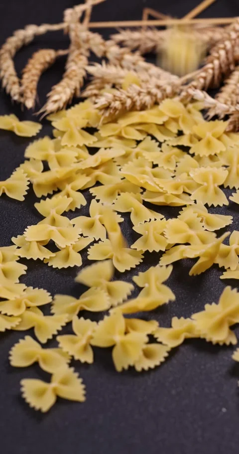 Farfalle pasta falling on black surface with wheat Stock Footage 302020628