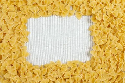 Farfalle pasta making a frame on rustic linen fabric Foto stock