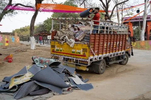 Faridabad, India - Febuary 1, 2020: Vendors toss rugs out of a truck, for sal Stock Photos