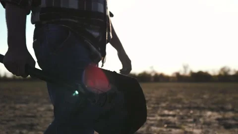 Farm agriculture concept. Farmer with a shovel in rubber boots walks across Stock Footage