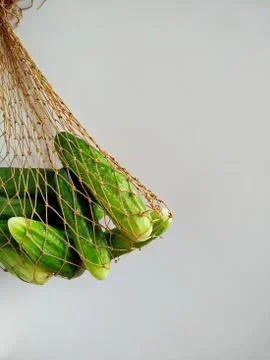 Farm cucumbers from the garden in a string bag on a white background Stock Photos