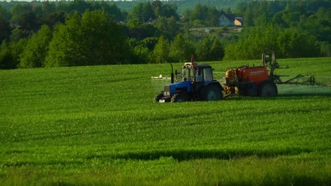 Farm equipment sprays crop fields during sunny day in rural area Vidéo 338430832