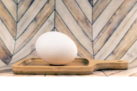 Farm fresh brown egg on a tiny cutting board with a faux wood background Stock Photos