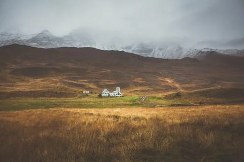 Farm in front of a empty mountain range with fog and snow. Lovely landscape.. Stock Photos