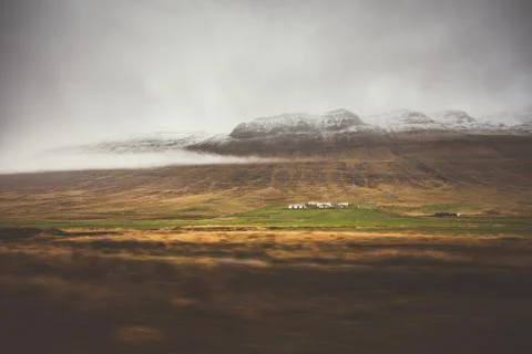 Farm in front of a empty mountain range with fog and snow. Lovely landscape.. Stock Photos