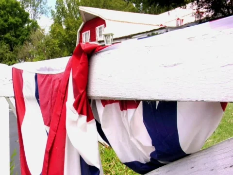 FARM HOUSE WHITE FENCE WITH FLAG DRAPPED Stock Footage
