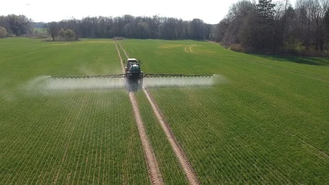 Farm tractor with sprayer spraying spring time wheat field, aerial Stock Footage 122979224