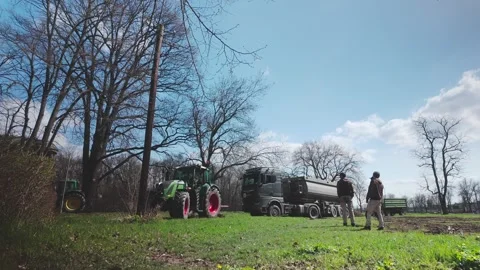Farm tractor struggles to pull heavy lorry stuck in muddy field Stock Footage 306362462