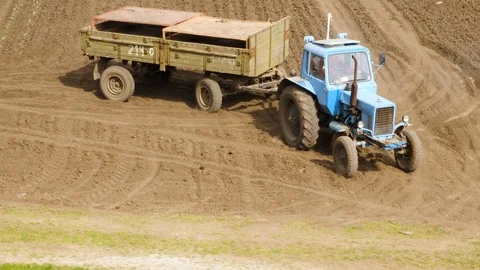 Farm Tractor With Utility Trailer Passing On Unpaved Rural Road Stockbeeldmateriaal 89905962