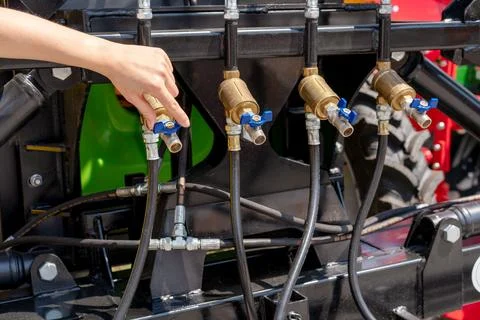 Farmer adjusting flow control valve on agricultural machinery. Valves of spra Stock Photos