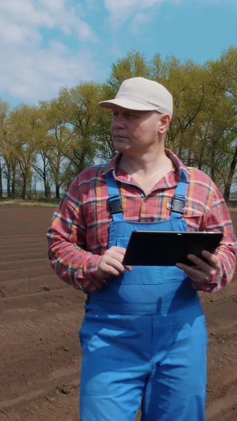 Farmer, agronomist stands between soil rows on farm field, testing quality of Stock Footage 309636359