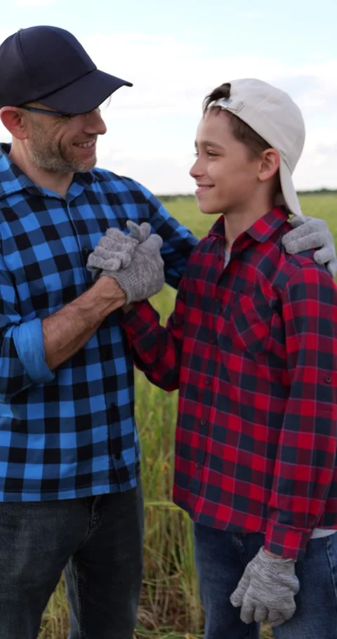 Farmer and son work together in wheat field, sharing smiles and teamwork Stock Footage 343855502