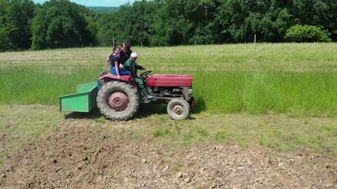 Farmer with apprentice riding tractor in farmland Video stock 130369360