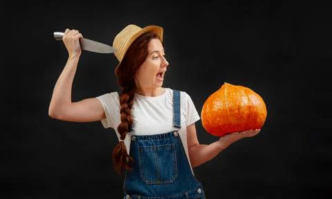 Farmer on black background attacks a ripe pumpkin with a sharp knife. Stock Photos