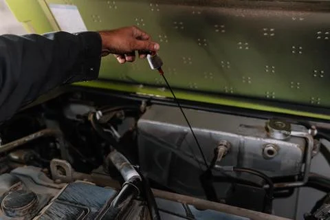 Farmer checking oil level of tractor engine during maintenance Foto stock
