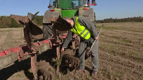 Farmer clean plow near to the tractor Stock Footage
